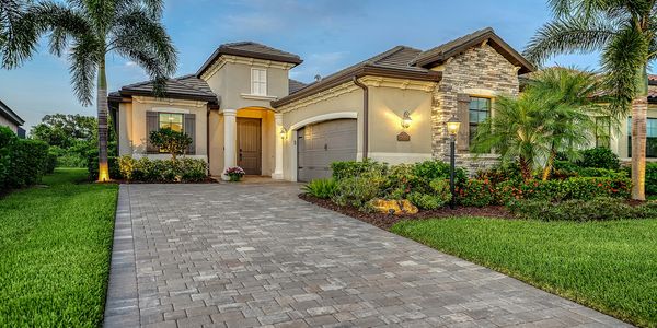 A modern suburban house with a paved driveway and lush landscaping.