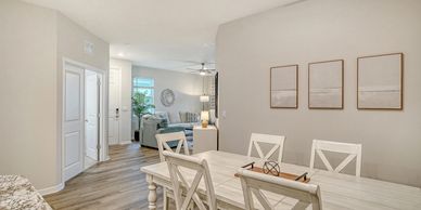 Bright dining area with white wooden furniture and neutral wall art.