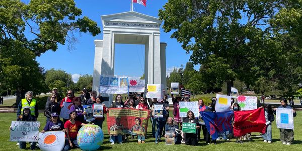 Group of activists holding climate change protest signs outdoors on a sunny day.