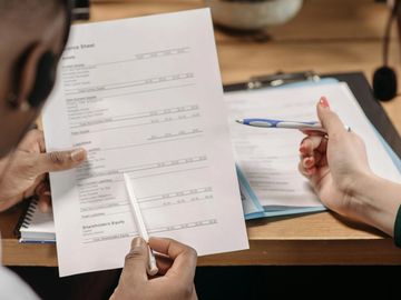 Man and woman sitting side-by-side reviewing administrative documents at a desk