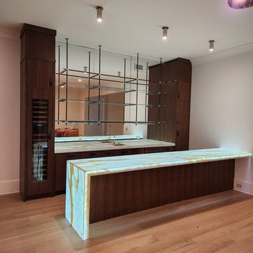 Modern kitchen with illuminated marble countertops and dark wood cabinets.