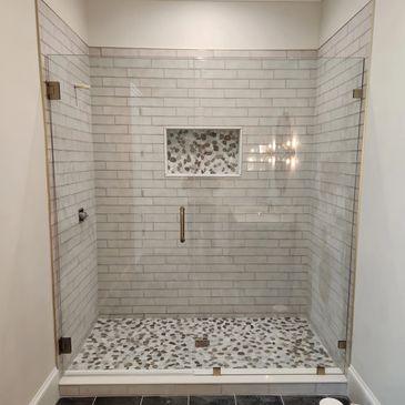 Modern walk-in shower with pebble floor and glass enclosure.