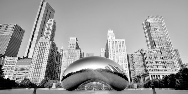 The Cloud Gate sculpture in Chicago with surrounding skyscrapers in black and white.
