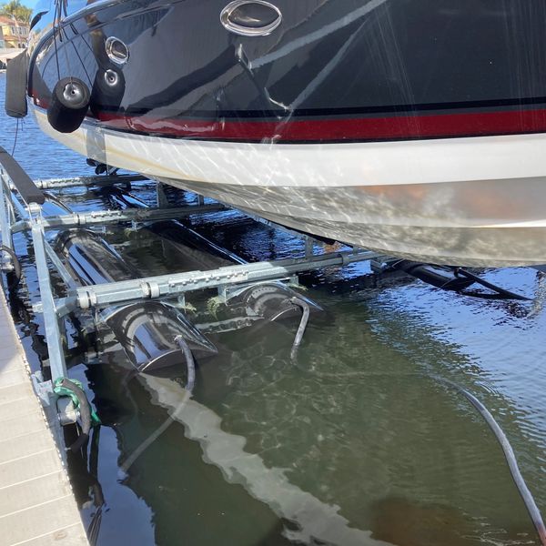 Boat on boat hoist lift, tanks and hoses on a dock on the CA Delta