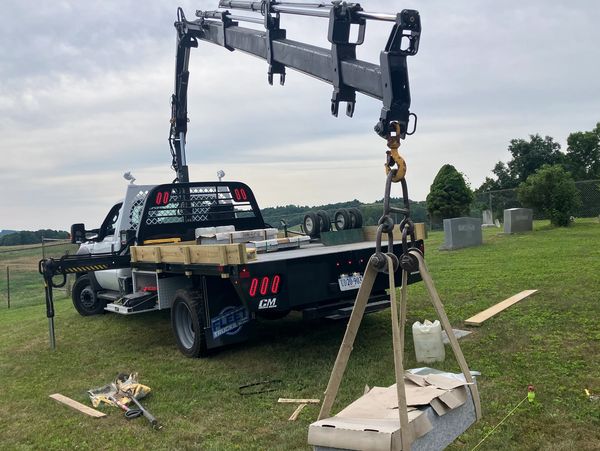 Crane lifting materials near a truck on grass.