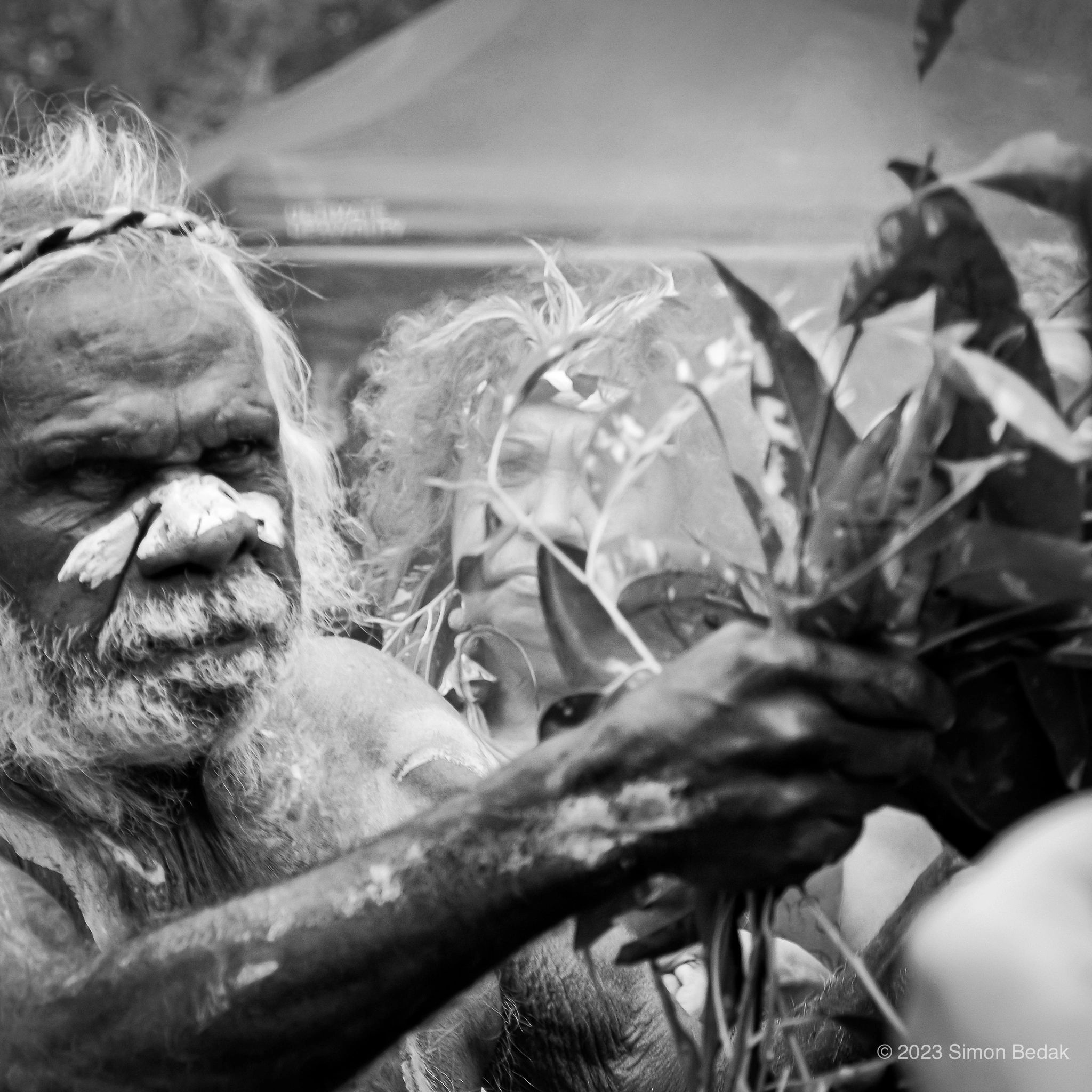 Black and white portrait of a person with traditional face paint and a headband.