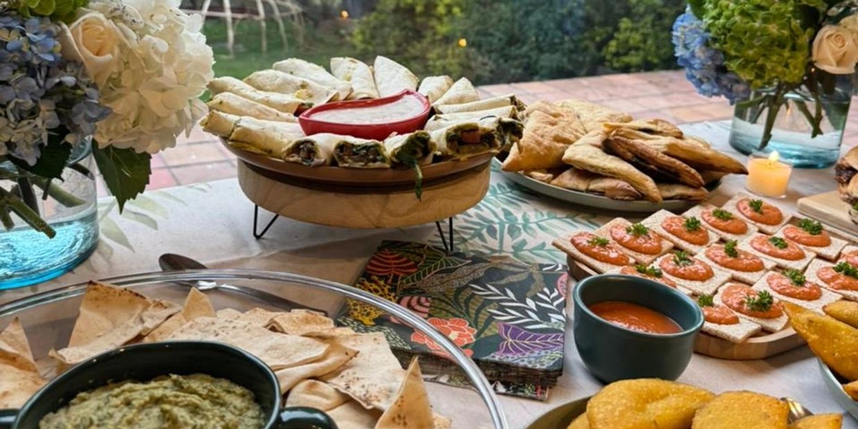 A table set with various appetizers and dips, decorated with flowers.
