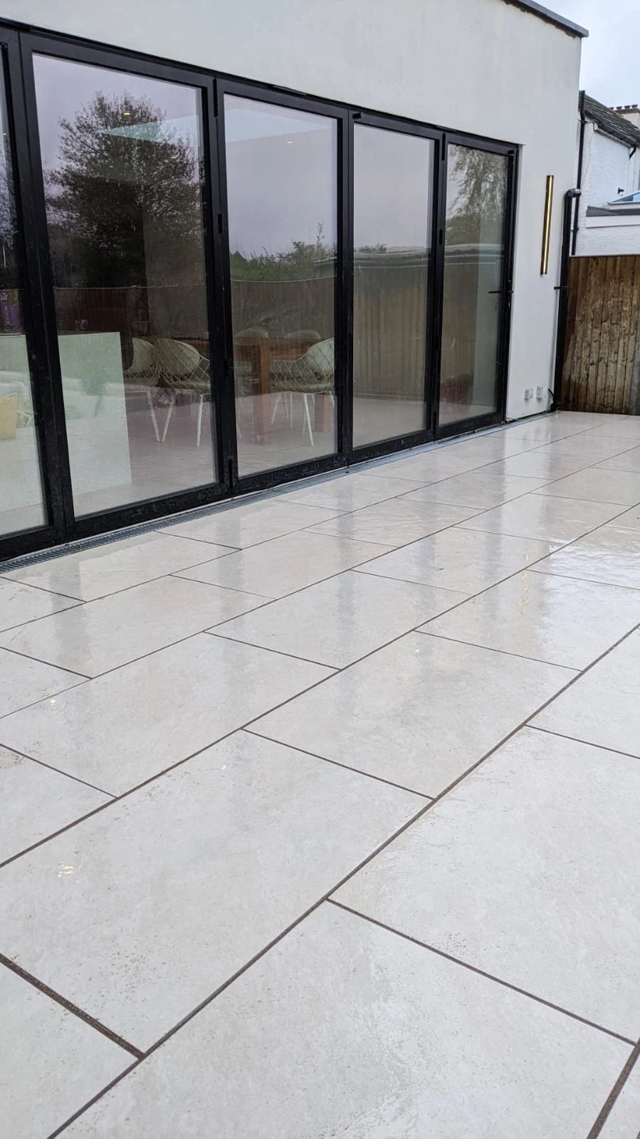 Modern outdoor patio with large glass doors and polished tiles.