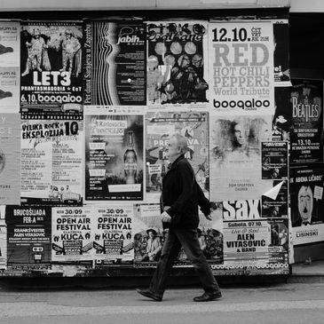 Man walking past a wall covered in posters.