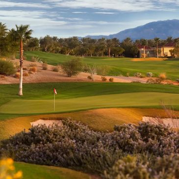 Scenic golf course with green fairways and mountains in the background.