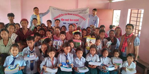 Group of children and adults holding school supplies in a classroom setting.