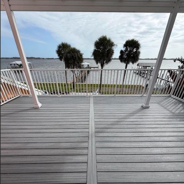 Deck overlooking water with palm trees and docks.