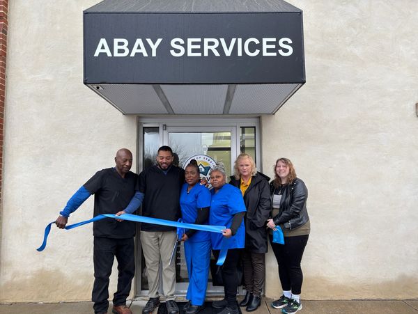 Ribbon-cutting ceremony at Abay Services with six people.