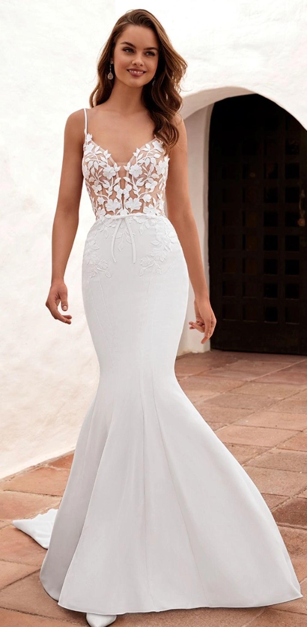 Elegant white mermaid wedding dress with floral applique bodice and thin straps.