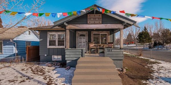 Small gray house with front porch and colorful prayer flags.