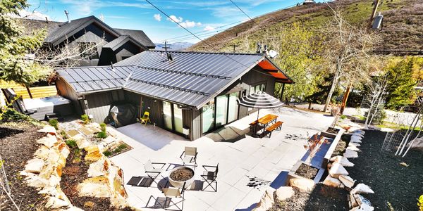 Modern house with outdoor seating and fire pit on a sunny day.