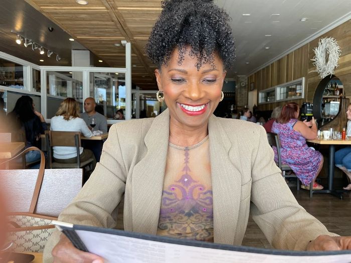 Woman smiling while looking at a menu in a cozy restaurant.