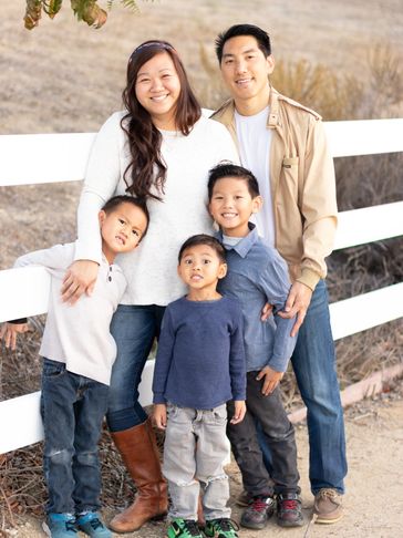 A husband and wife, with their three kids, smiling