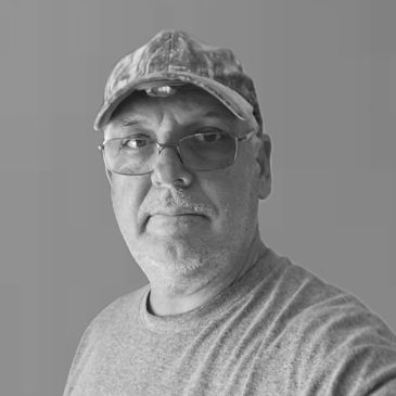 Black and white portrait of a man wearing glasses and a cap.