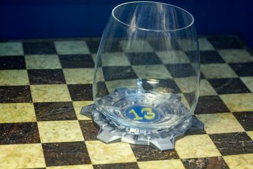Empty glass on a checkered surface with a coaster numbered 13.