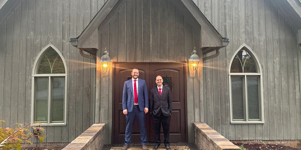 Photo of two men standing in front of a church.