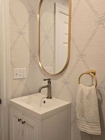 Elegant bathroom corner with gold-accented mirror and towel ring.