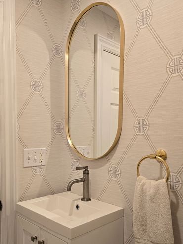 Elegant bathroom corner with gold-accented mirror and towel ring.