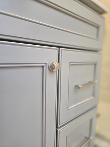 Close-up of a gray cabinet with silver handles and a knob.