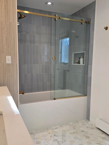 Modern bathroom with glass shower doors and blue tiled walls.