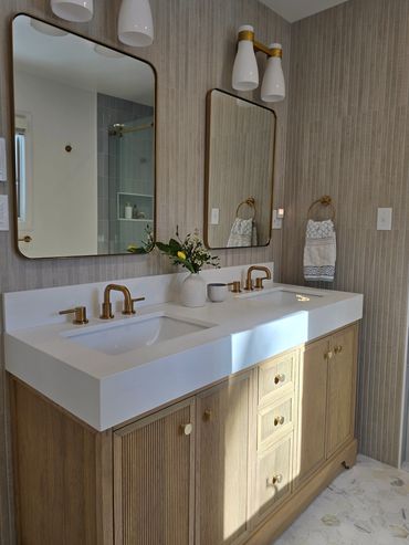 Modern bathroom vanity with dual sinks, gold fixtures, and large mirrors.