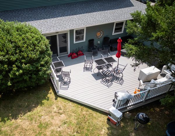 Aerial view of a house with a large outdoor deck furnished with tables and chairs