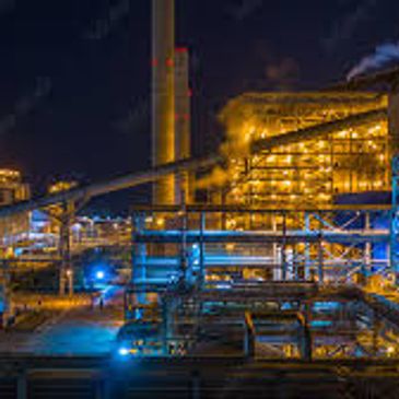 Industrial factory at night with illuminated structures and steam.