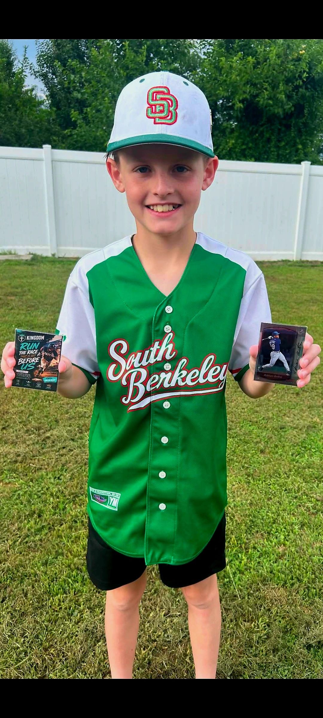 Boy in baseball uniform holding cards.