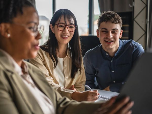 Three colleagues engaged in a discussion while reviewing a document together.