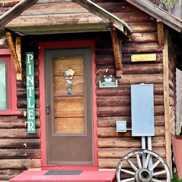 Rustic wooden cabin entrance with Pintler sign.