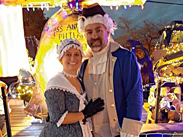 Couple dressed in colonial attire at a nighttime event.