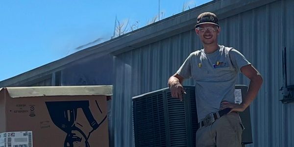 Worker standing on a rooftop with HVAC equipment.