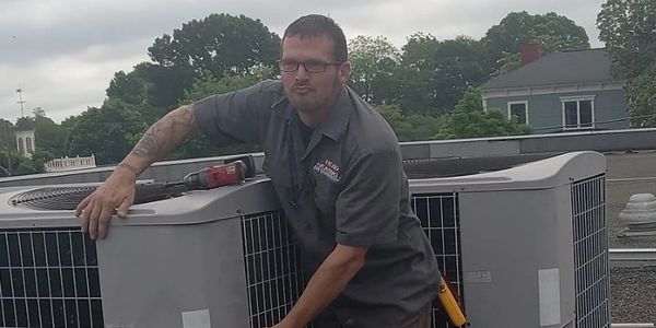 Technician repairing rooftop air conditioning units.