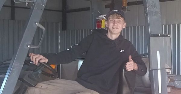 Young man sitting and giving thumbs up inside a vehicle.