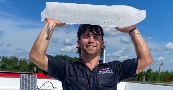 Man holding a large ice block above his head.