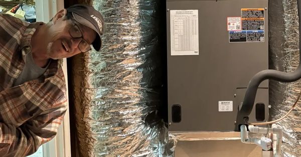 Man smiling next to HVAC system and ductwork.