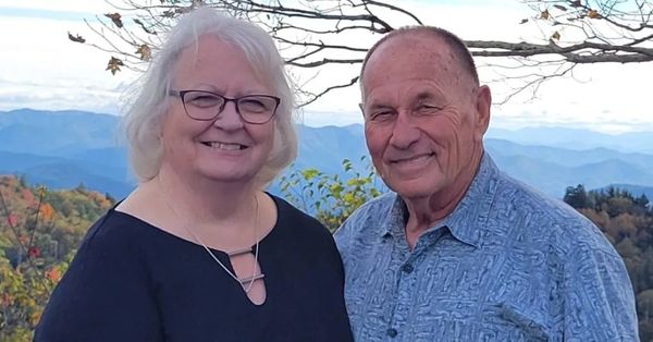 Smiling elderly couple outdoors with mountains.
