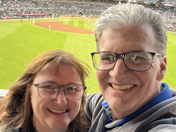 Couple smiling at a baseball game.