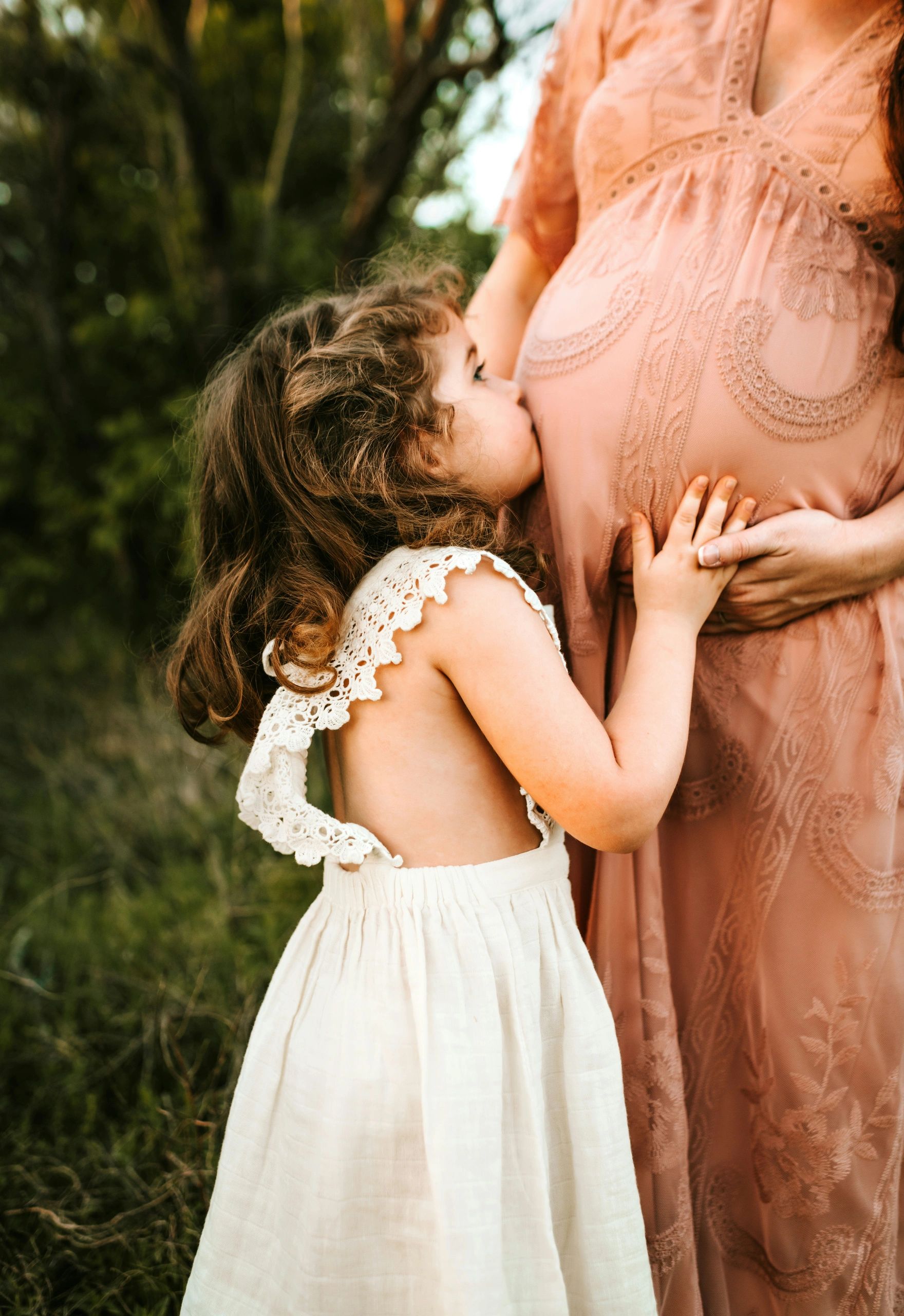 A child kisses her pregnant mother's belly