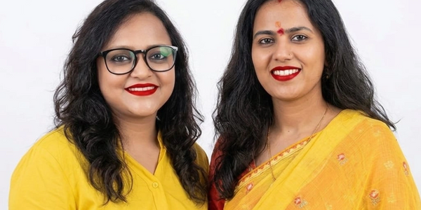 Two women in yellow outfits smiling against a white background.