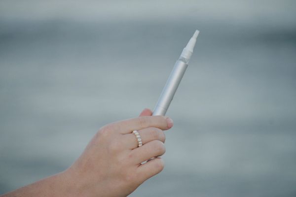 Hand holding a sleek silver pen with a blurred background.