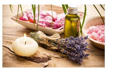 A relaxing spa setup with lavender, candle, oil, and pink bath salts.