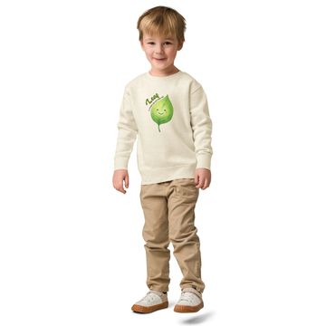 Young boy smiling, wearing a sweatshirt with a green leaf design.