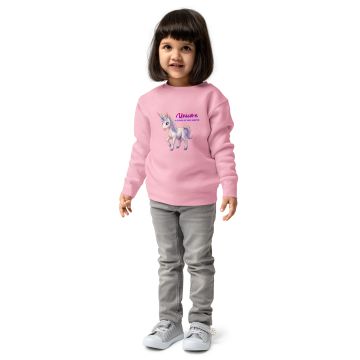 Little girl in a pink unicorn sweatshirt and gray jeans.
