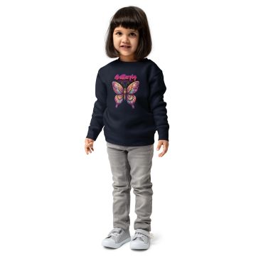 A little girl wearing a butterfly-themed sweatshirt and striped shoes.